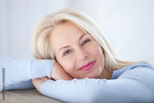 Active beautiful middle-aged woman smiling friendly and looking in camera. Woman's face closeup. Realistic images without retouching with their own imperfections. Selective focus. photo