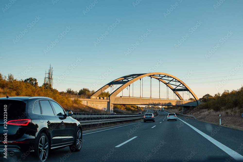 Driving in the morning on the german autobahn highway with a bridge and cars. Road trip scenery