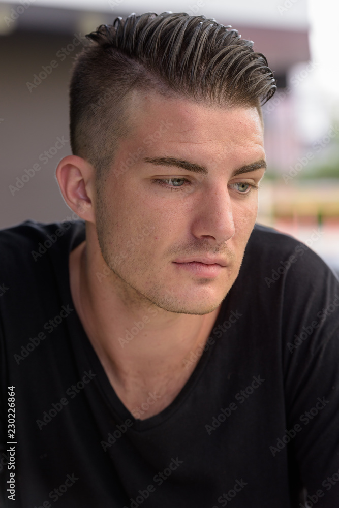 Young handsome man looking down while thinking outside the coffe Young handsome man looking down while thinking outside the coffe