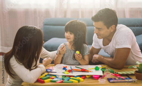 Portrait of happy family daughter girl is learning to use colorful play dough together with parent