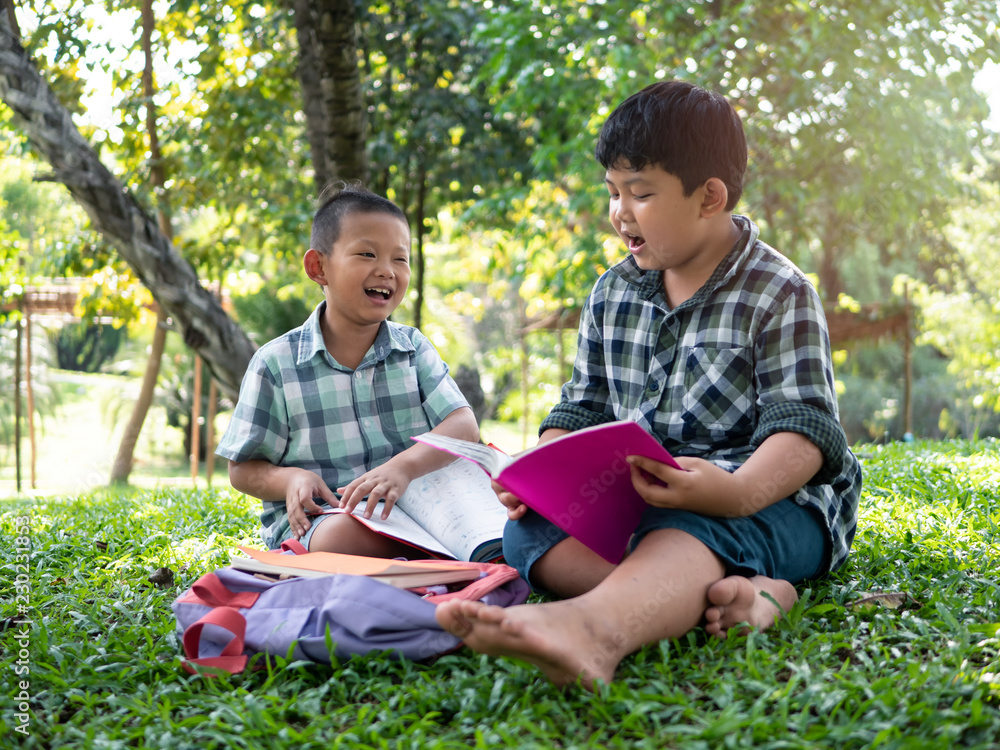 Cute two asian student boy reading book in the nature park with sunlight background, people, learning, relax, education and Natural classroom concept.. Cute two asian student boy reading book in the nature park with sunlight background, people, learning, relax, education and Natural classroom concept..