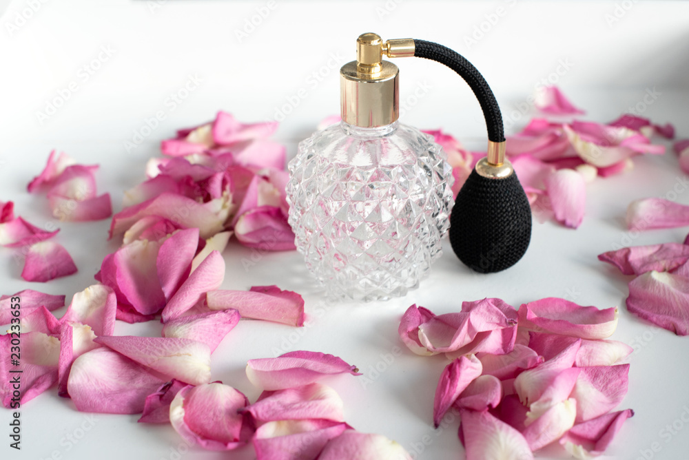 Altmodischer Vintage Parfumflakon aus Glas mit Zerstäuber in schwarz und  gold auf weißem Tablett mit rosafarbenen Rosenblättern dekoriert Stock  Photo | Adobe Stock