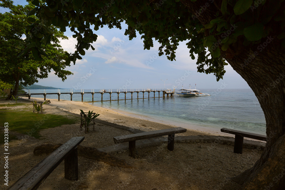 Pier to Sumilon Island Cebu Philippines, in a tranquil scene under a big tree gives shadow to travelers while wating for the boat ride to the island resort