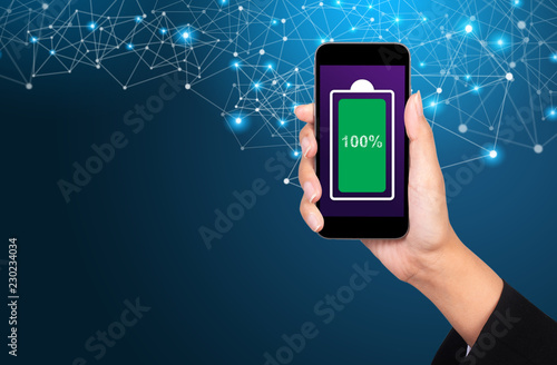 Full charged battery green icon in a mobile phone screen. Woman holding it in the hand