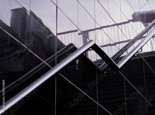 Staircase stainless steel handrails. Modern stairs with Stainless steel railings in a new modern Underpass . Reflection and shadows on the glass wall. Modern design.