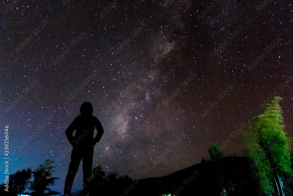 Silhouette of a standing human looking milky way at the night time