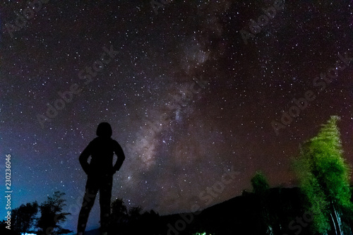 Silhouette of a standing human looking milky way at the night time