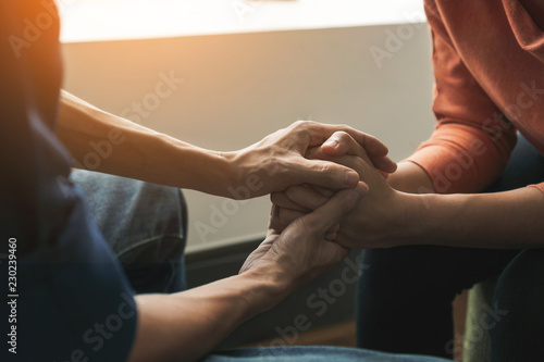 PTSD Mental health concept, Psychologist sitting and touch hand young depressed asian woman for encouragement near window with low light environment.Selective focus.