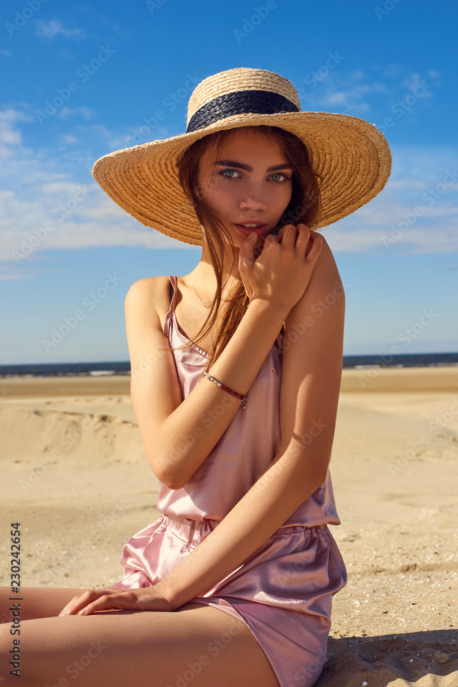 young girl on the beach posing with a hat