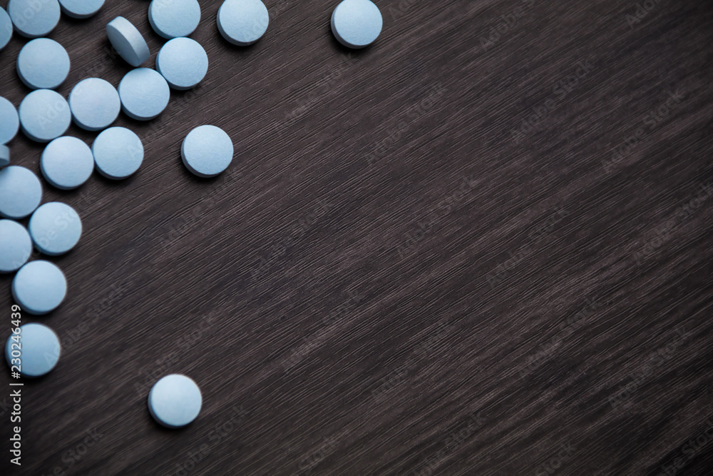 Medication pills in a row against a wood background.