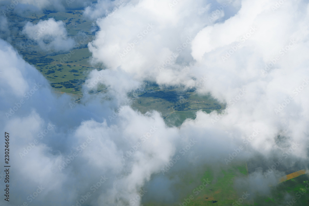 Landscape, the surface of the earth through the clouds from an airplane window.