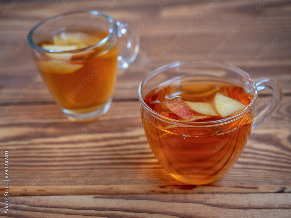 Tea with apples in glass mugs on wooden background Tea with apples in glass mugs on wooden background