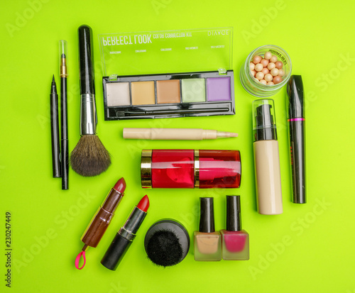 The composition of accessories, makeup cosmetics on a bright green background. Top view. 