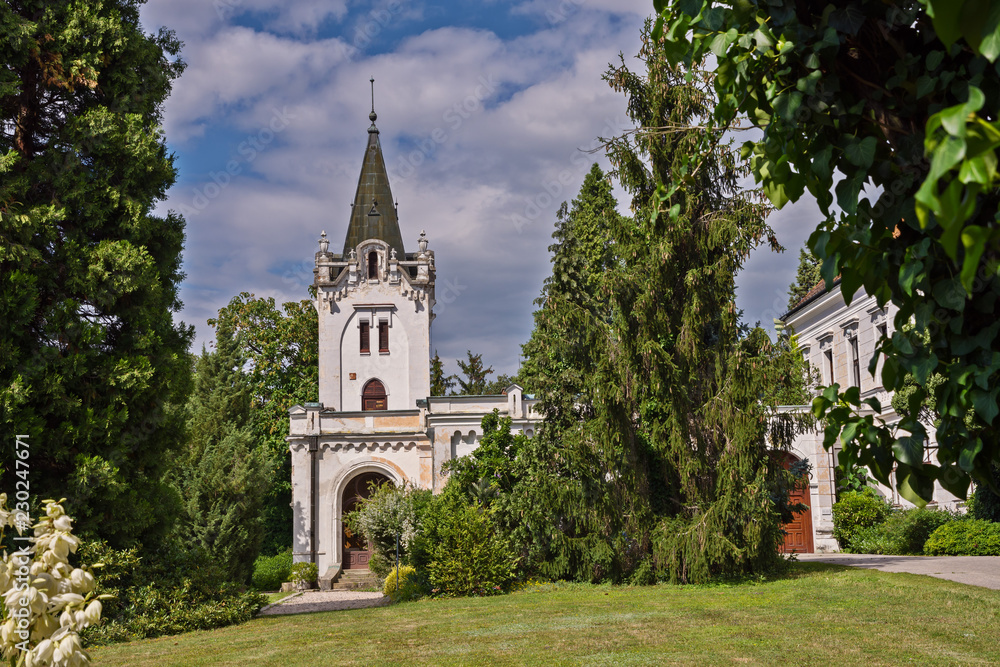 Naklejka premium chapel with bell tower among the trees in the park and blue sky