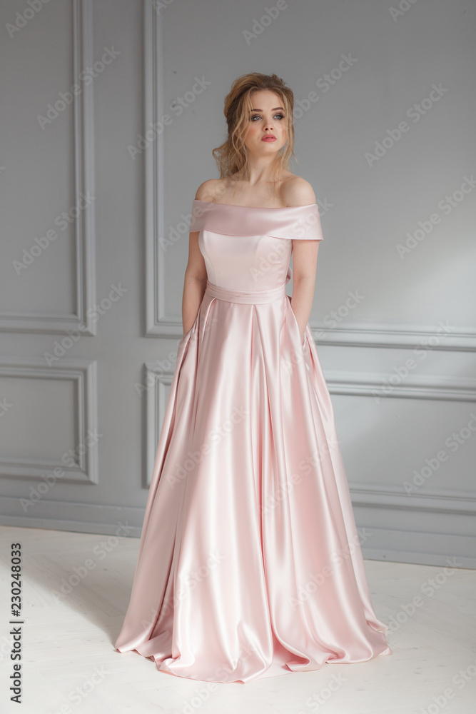Full-lenght portrait of bride in beige silk wedding dress posing on gray wall background Full-lenght portrait of bride in beige silk wedding dress posing on gray wall background