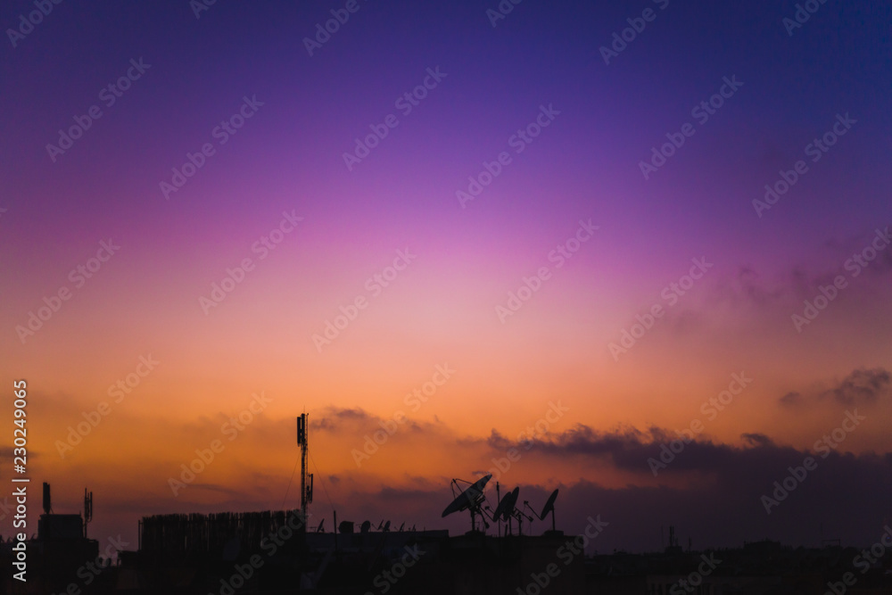 silhouette of dishes against sky in sunset