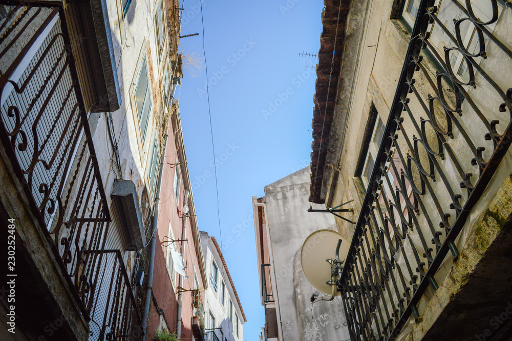Fototapeta premium Typical portuguese streets, apartment windows and houses on traditional district scene in Lisbon, Portugal. historical structure view.