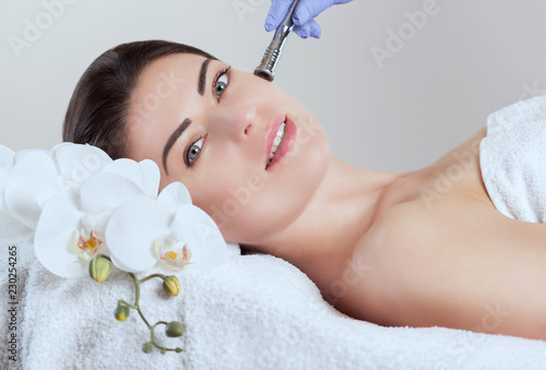The cosmetologist makes  Microdermabrasion procedure of the facial skin of a beautiful, young woman in a beauty salon.Cosmetology and professional skin care.