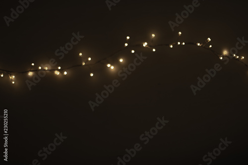 Abstract Christmas lights on  black  background. Defocused  Glowing light bulb garland, copyspace