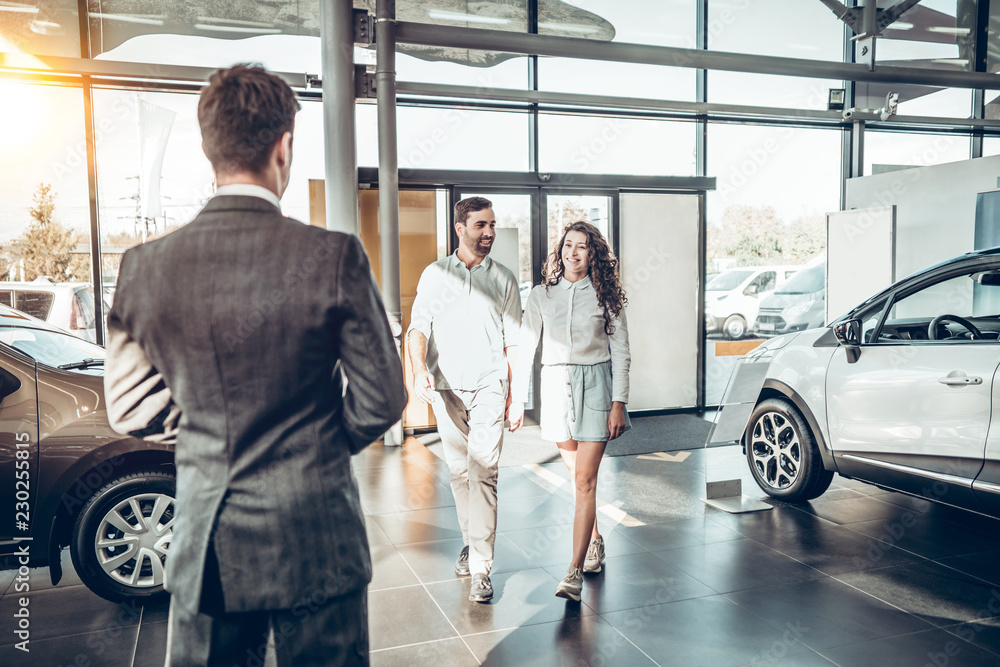young family comes into Car dealership to choose the car to buy it. young family comes into Car dealership to choose the car to buy it.