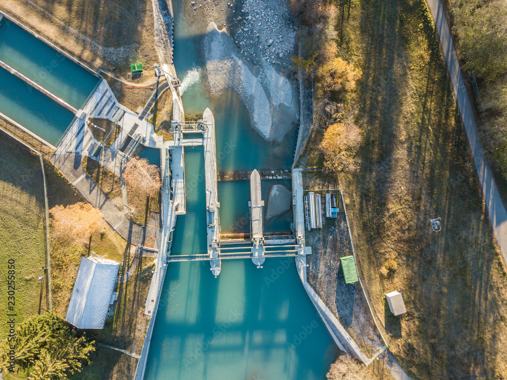 Fototapeta premium Aerial view of river dam in small river in Switzerland in evening sunlight