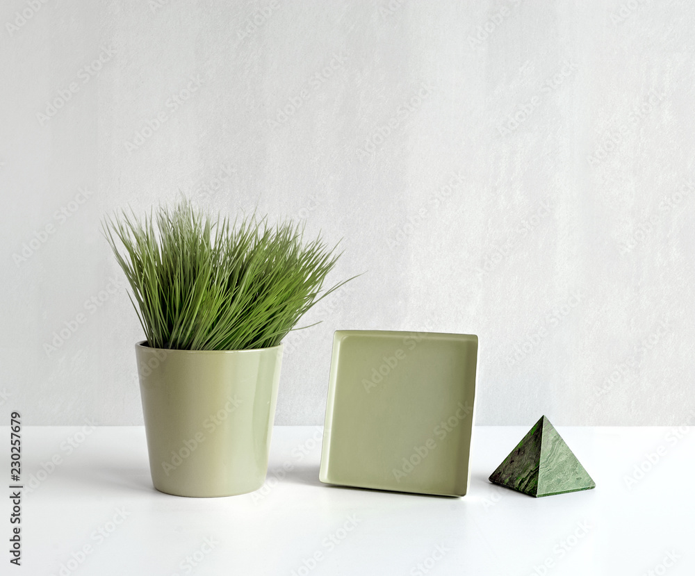 Fototapeta premium Still life of grass in flowerpot, metal tray and marble pyramid.