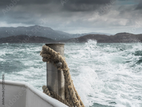 Stormy sea on a boat journey, closeup of a rope infront of scottish cost and landscape photo