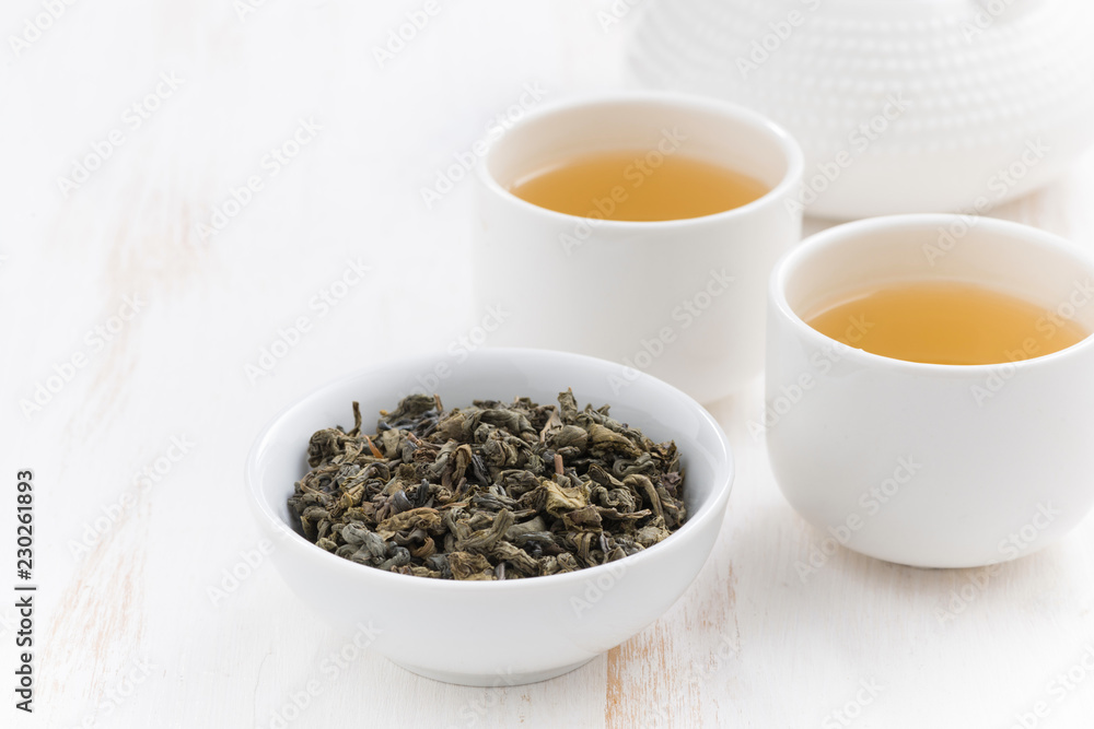cups and teapot with green tea on a white wooden background, close-up cups and teapot with green tea on a white wooden background, close-up