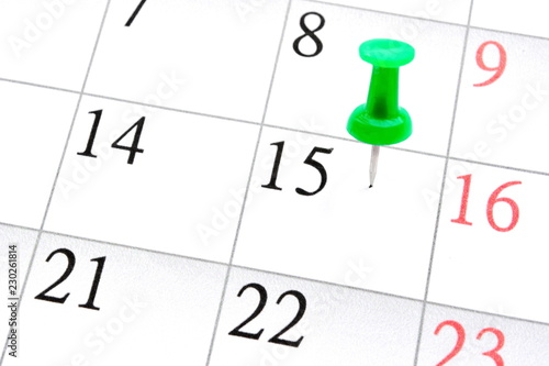 stuck stationery green pushpin in a sheet of monthly calendar