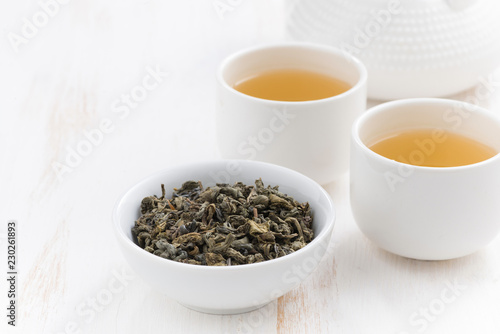 cups and teapot with green tea on a white wooden background, close-up