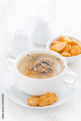 delicious mushroom cream soup with croutons on white table, vertical