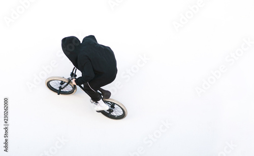 Portrait of a rider in dark clothes riding on a bmx on a white wall. bmx freestyle on a white background. Bmx concept