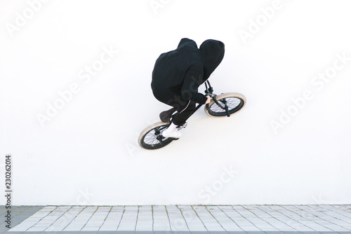 BMX rider rides a bicycle on the white wall. Young man is doing tricks on BMX. BMX freestyle