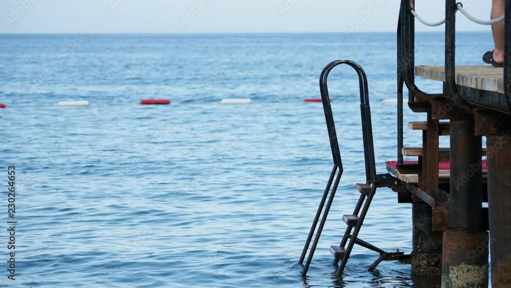 Rusty stairs from pontoon into water. Man tourist came to the edge of the flooring. Turkey. Rusty stairs from pontoon into water. Man tourist came to the edge of the flooring. Turkey.