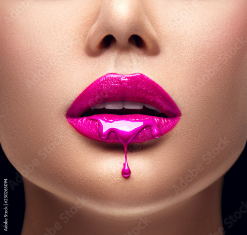 Pink lipstick dripping. Lipgloss dripping from sexy lips, Purple liquid drops on beautiful model girl's mouth, creative abstract makeup