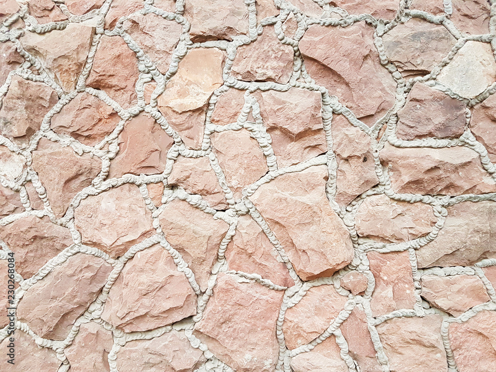 Fototapeta premium Ancient medieval stone masonry. Texture of a fragment of a wall of an old structure. A background for design and creative work. Decoration and exterior decoration of the building. Construction works.