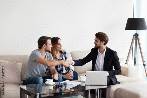 Young couple, family at meeting with realtor, interior designer, decorator, landlord making deal. Husband handshaking with man in suit. Concept of meeting with client, customer