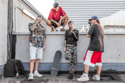 Valokuva group of rappers posing against the wall on the metal rooftops