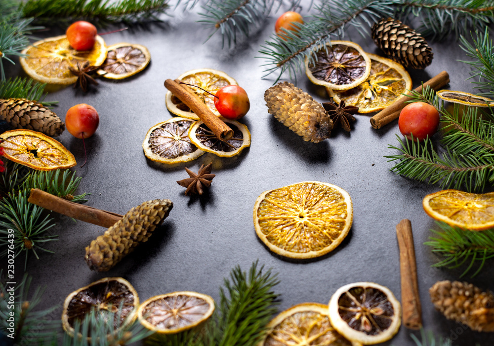 Sliced dried orange with christmas pine branches on dark texture surface. Holiday background. Sliced dried orange with christmas pine branches on dark texture surface. Holiday background.