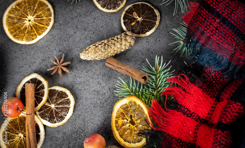 Sliced dried orange with christmas pine branches and scarf on dark texture surface. Holiday background.