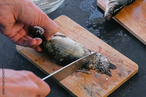 Man cleans carp from the scales. Close-up hands. Cooking a fish.