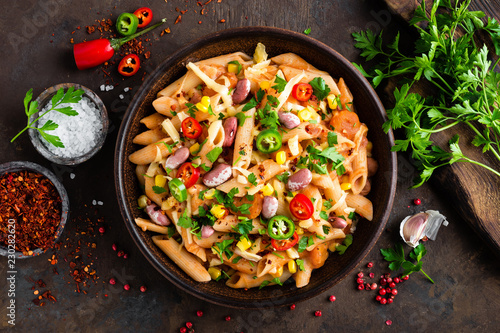 Spicy pasta penne bolognese with vegetables, beans, chili and cheese in tomato sauce
