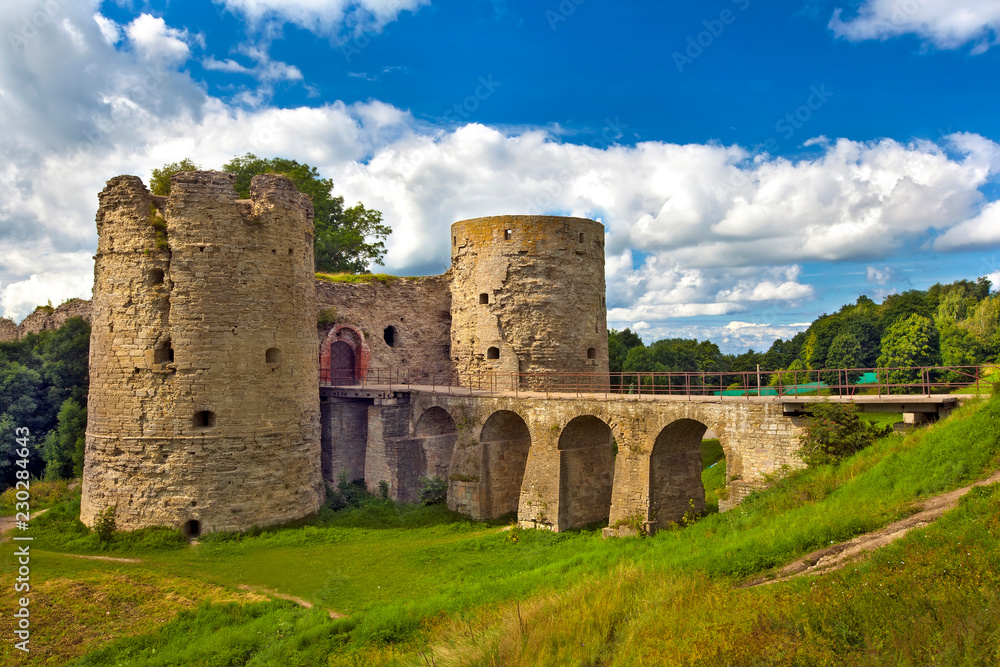 Monument of medieval defensive architecture. A stone towers with closed gate between them, bridge with arches over the moat. Koporye Fortress, Leningrad District, Saint Petersburg, Russia.