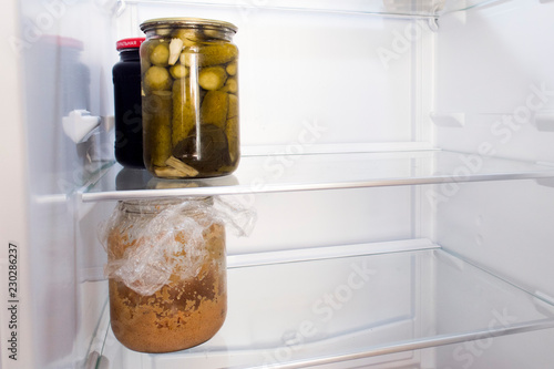 A jar of cucumbers, a jar of jam and a jar of fish caviar in a fridge