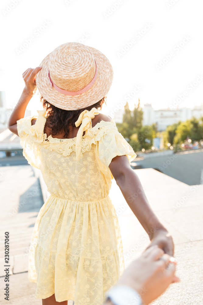 Back view photo of african young woman walking outdoors