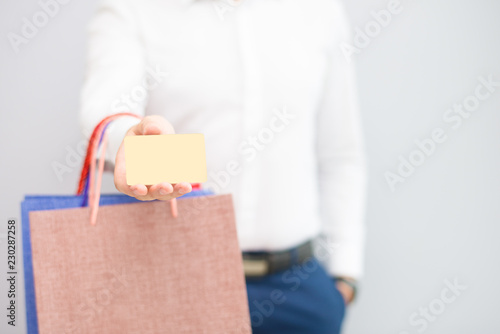 Closeup of man showing credit card and holding shopping bags. Buyer holding purchases. Shopping and payment concept. Isolated cropped view on grey background.