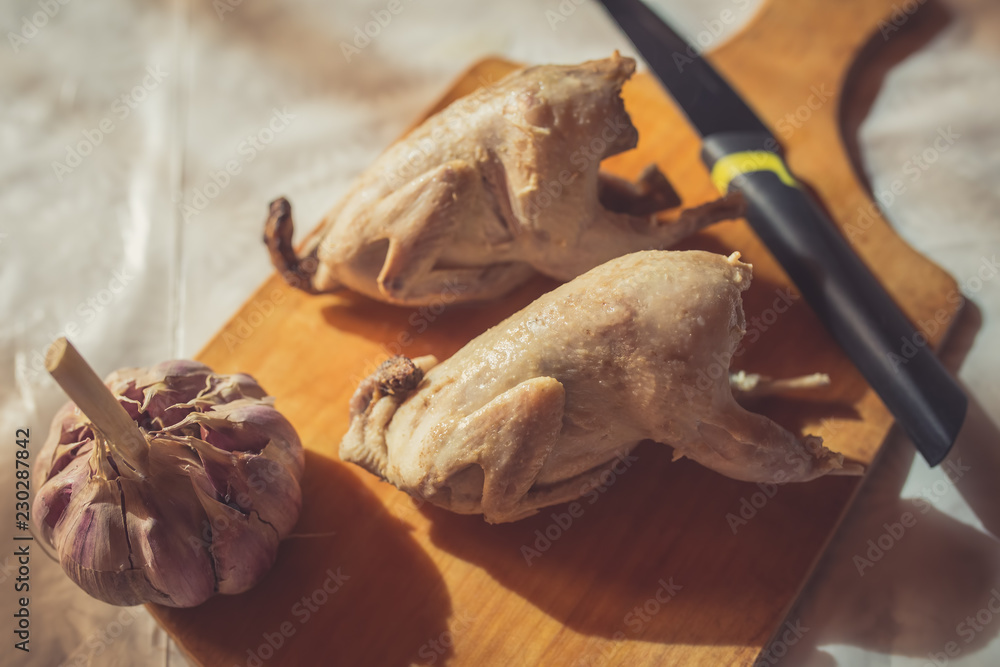 Two whole boiled quails lie on a cutting board as an example of diet food