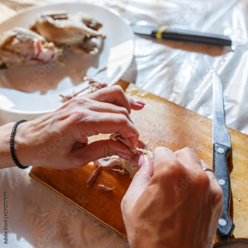 Woman by hands is disjoining the quail meat in the kitchen photo