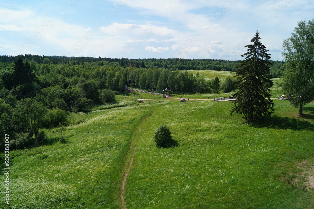 Green meadow with a path to the source of the Volga river