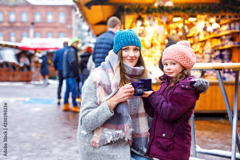 Young woman and cute kid girl with cup of steaming hot chocolate or children punch